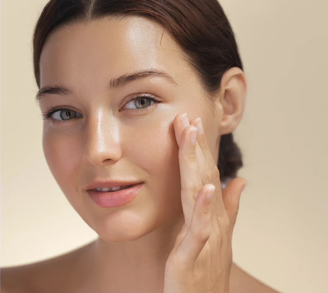 Woman applying skincare product on face.
