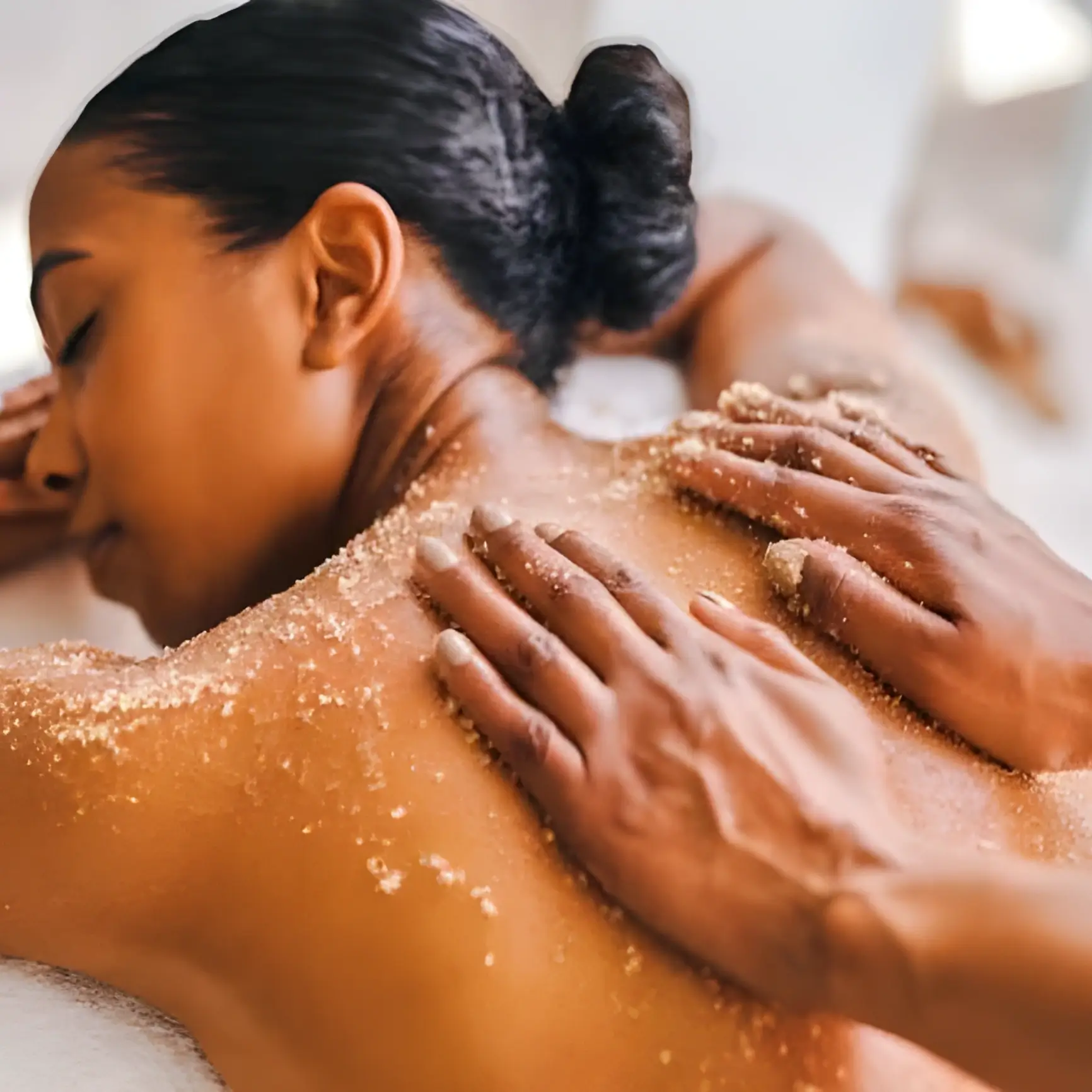 Woman receiving exfoliating back massage treatment.